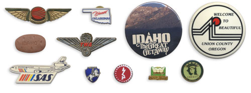 TWA wings, SAS wings, an Idaho potato button, Discover Oklahoma!, Idaho The Great Getaway, Welcome to Beautiful Union County, Vienna pin, Berlin Jewish Museum pin, Oregon Trail pin, Statue of Liberty pin