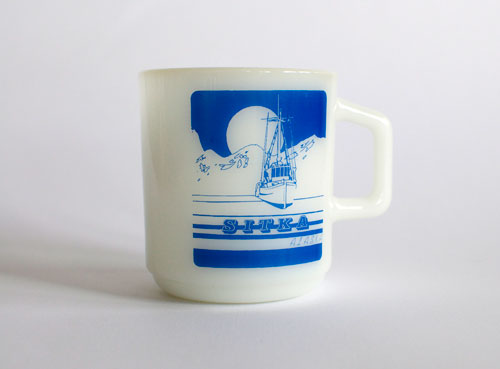 Sitka, Alaska mug - scene of a boat, some mountains, and either a sun or a moon.